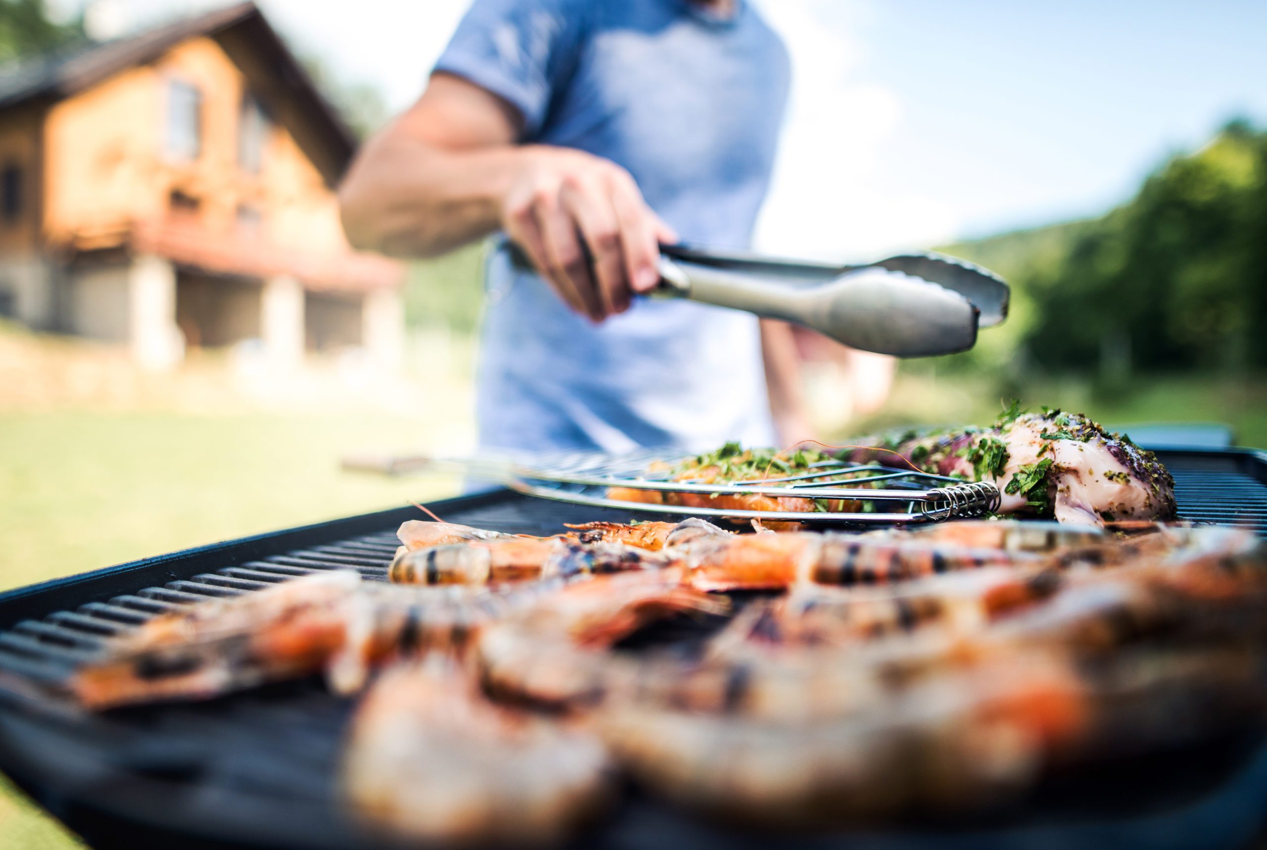 Blog - Unrecognizable man cooking seafood on a barbecue grill in the backyard.