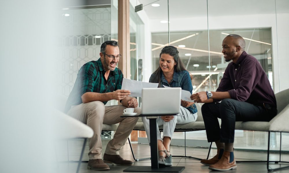 Casual meeting of smiling diverse business team analyzing financial data