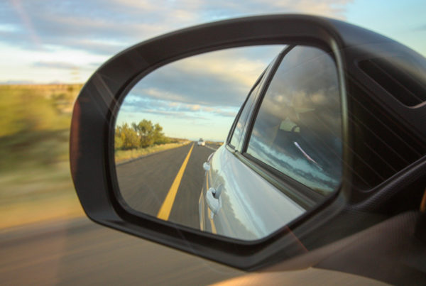 Blog - Car Review Driver Mirror with a View of the Road Behind Car on a Nice Day