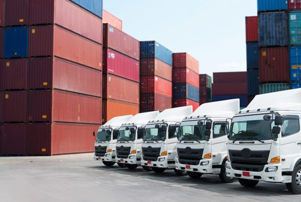 Blog - Fleet of White Trucks in front of Storage Containers in a Large Log